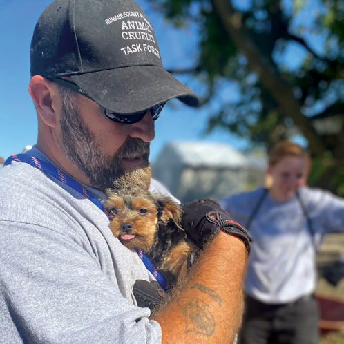 man with Animal Cruelty Task Force hat holding rescued puppy